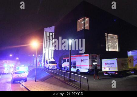 Essen, Allemagne. 21st févr. 2022. De nombreuses ambulances sont garées devant un auditorium abritant les résidents évacués d'un complexe d'appartements en feu. Dans le quartier ouest de la ville, tout un immeuble était en flammes depuis le début de lundi matin. L'incendie s'est déclaré peu après minuit sur Bargmannstrasse. Les flammes se répandent rapidement sur plusieurs étages. On ne sait toujours pas si des personnes ont été blessées. Credit: Stephan Witte/KDF-TV/dpa/Alay Live News Banque D'Images