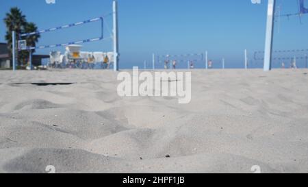 Joueurs jouant au volley-ball sur la plage, jeu de volley-ball avec balle et filet, côte de Californie, États-Unis.Des personnes actives défocacées sur le terrain de sport, sur la rive sablonneuse de l'océan.Arrière-plan cinemagraph en boucle sans couture. Banque D'Images