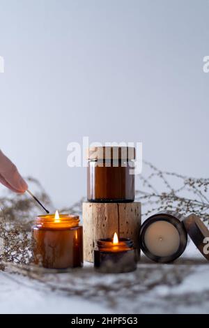 Un ensemble de bougies de soja dans un pot en verre brun avec un couvercle en bois. Bougie aromatique brûlante. Des bougies lumineuses avec un match. Confortable et agréable. Aromathérapie. Banque D'Images