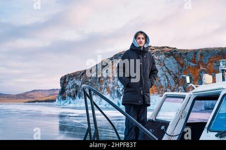 L'adolescent se tient sur un aéroglisseur sur la glace du lac Baikal. Banque D'Images