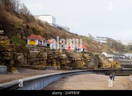 Deux femmes parlant et marchant sur la plage à Scarborough près du Spa et des cabanes de plage Banque D'Images