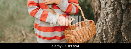 kid girl champignon picker est à la recherche et la cueillette des champignons avec le panier dans la forêt d'été ou des bois. enfants survivalistes rassemble un champignon sauvage harv Banque D'Images