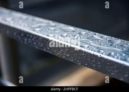 Gouttes de pluie sur une surface métallique. La rosée tombe sur une rampe en acier de près. Banque D'Images