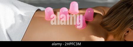 petite vue de la jeune femme avec des tasses de massage roses sur le dos recevant un massage sous vide, bannière Banque D'Images