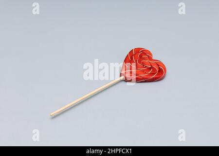 lollipop en forme de coeur rouge repose sur un fond bleu. Photo de haute qualité Banque D'Images