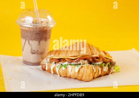 Sandwich croissant aux brioches de poulet grillées avec latte glacée et mini-beignet fourré. Banque D'Images