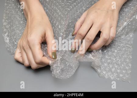 femme débordant bulle envelopper dans ses mains sur un fond gris. Photo de haute qualité Banque D'Images