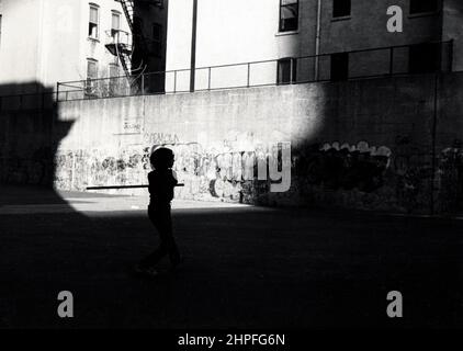 Silhouette d'un jeune adolescent jouant du stickball et utilisant un bâton de poulet comme une chauve-souris. À Park Slope, Brooklyn, New York. Vers 1978 Banque D'Images