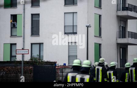 Essen, Allemagne. 21st févr. 2022. Une femme nettoie les fenêtres pendant que les pompiers sont en service. Dans le quartier ouest de la ville, tout un immeuble était en flammes depuis le début de lundi matin. L'incendie s'est déclaré peu après minuit à Bargmannstraße. Les flammes se répandent rapidement sur plusieurs étages. On ne sait toujours pas si des personnes ont été blessées. Credit: Fabian Strauch/dpa/Alay Live News Banque D'Images