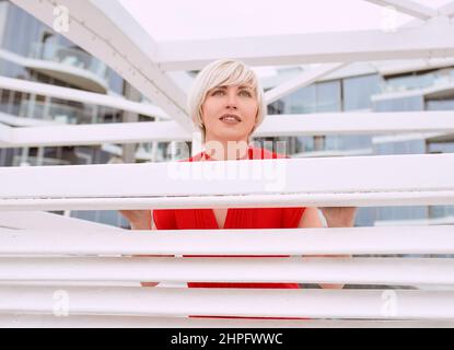 portrait de jolie fraîche belle cheveux courts blonde femme en rouge corail robe près bois blanc arbre pour la plage Banque D'Images