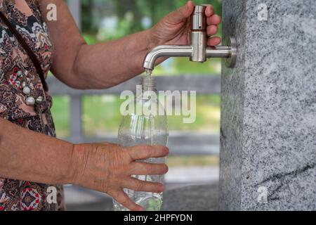 La femme verse de l'eau dans une bouteille en plastique. Gros plan Banque D'Images