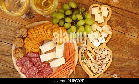 En-cas pour le vin. Assiette de fromage et de viande. Saucisses, fromage, noix, raisins, crackers sur fond de bois Banque D'Images
