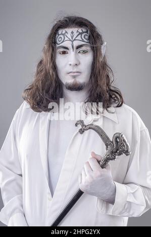 Le Performer illusionniste de fantaisie. Performance peinte par le corps en costume noir et blanc avec chapeau et bâton Banque D'Images