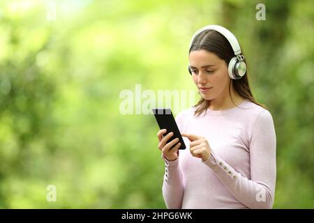 Femme portant un casque pour écouter de la musique sur fond vert Banque D'Images