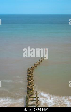 Vue sur la mer du Nord depuis le sommet de la falaise à Overstrand, Norfolk, Angleterre, Royaume-Uni, lors d'une journée ensoleillée et lumineuse avec une groyne à pattes en premier plan Banque D'Images