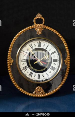 Une horloge ancienne avec cadran blanc sur une table avec réflexion. Articles ménagers sur fond noir Banque D'Images