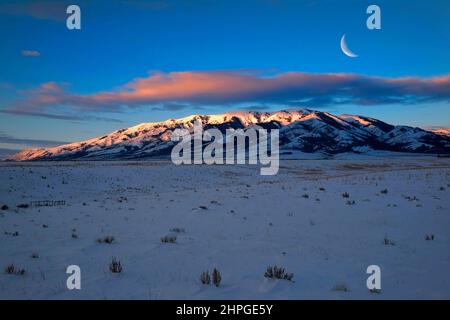 Lever ou coucher de soleil lumière du soleil lumière du soleil en hiver sur les montagnes enneigées avec croissant de lune Banque D'Images