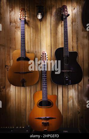 Guitares acoustiques de jazz gitane admirablement pendues sur un mur en bois. Banque D'Images