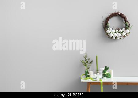 Magnifique décor de Pâques sur la table et couronne accrochée au mur clair Banque D'Images