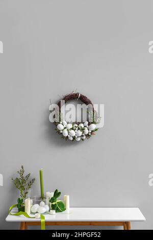 Magnifique décor de Pâques sur la table et couronne accrochée au mur clair Banque D'Images