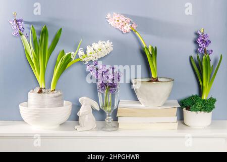 Jacinthe blanche dans un grand bol en porcelaine, figurines de lièvres et un oiseau, sont sur la cheminée contre le mur bleu foncé. Mise en page. Concept de ressort Banque D'Images