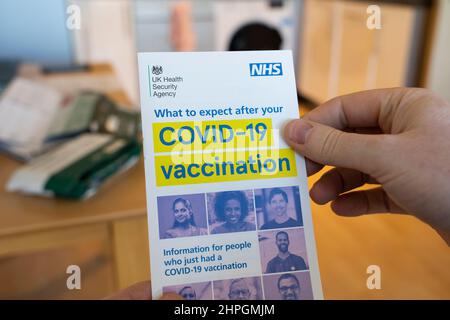 Les mains d'un homme tenant une agence de sécurité du gouvernement britannique et un dépliant du NHS fournissant des conseils sur ce qui se passe après une vaccination contre le coronavirus Covid-19 Banque D'Images