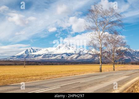 Route à travers le paysage avec des montagnes enneigées en arrière-plan. Parc national de High Tatras, Slovaquie, Europe. Banque D'Images