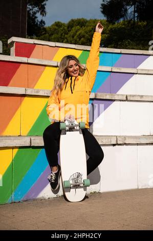 Portrait d'une femme joyeuse avec un skateboard sur des escaliers colorés Banque D'Images