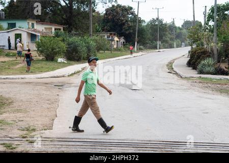 Un jeune cow-boy marche près d'une piste de train avec des crapules sur ses livres à Trinidad, Cuba. Banque D'Images