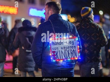 Schwerin, Allemagne. 21st févr. 2022. Avec plusieurs centaines de personnes, un homme marche dans le centre-ville lors d'une manifestation contre les mesures de protection de Corona, portant un panneau indiquant « Veuillez garder les mains hors de nos enfants ». Malgré les relaxations annoncées pour mars 2022, les critiques de la politique de Corona manifestent à nouveau dans diverses villes de Mecklembourg-Poméranie-Occidentale. Ici, une éventuelle exigence générale de vaccination et les restrictions Corona encore en place dans de nombreuses régions font l'objet de critiques. Credit: Jens Büttner/dpa-Zentralbild/dpa/Alay Live News Banque D'Images