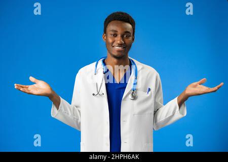 Afro-américain docteur homme portant le stéthoscope debout sur fond bleu sans cluse avec les bras levés Banque D'Images