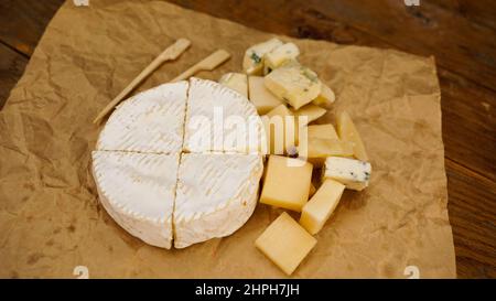 Différentes variétés de fromage. Fromage français doux de camembert et d'autres types sur papier artisanal avec brochettes en bois pour la nourriture. Banque D'Images