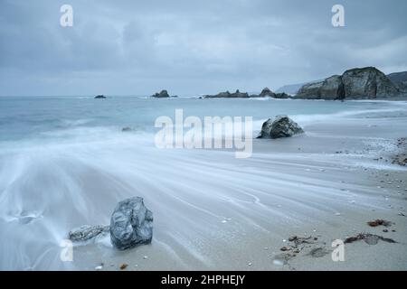 Vue longue exposition d'un rivage brumeux de l'Atlantique près de Cabo Ortegal en Galice, Espagne, avec un mouvement de l'eau lisse et des formations rocheuses côtières dispersées Banque D'Images