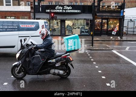 Le pilote de livraison de Deliveroo se rend le long d'un Londres très animé lors d'une journée d'hiver humide. Banque D'Images