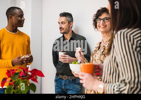 Divers groupes de personnes prenant une pause déjeuner dans un bureau. Banque D'Images