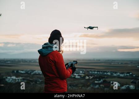 Pilote femelle utilisant une télécommande pour piloter le drone au coucher du soleil Banque D'Images