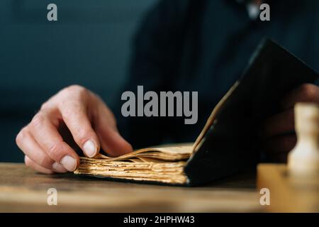 Gros plan court de vieux vieux hommes méconnaissables, ouvert de vieux livres et tournant des pages assis à table. Banque D'Images