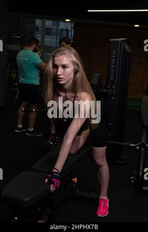 RUSSIE, MOSCOU - 11 FÉVRIER 2022: L'entraînement dirigé par un instructeur aide un beau client à effectuer des exercices dans un club de fitness, le concept de jouer du sport Banque D'Images