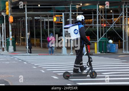 Un frigo personne de livraison pas plus sur un e scooter faire une demande rapide, sur demande livraison à New York, 20 févr. 2022. q commerce Banque D'Images