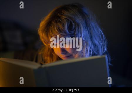 Un enfant lit le conte de fées dans un livre. Petit garçon dans la salle de séjour regardant des photos dans un livre d'histoire. Enfant faisant ses devoirs à l'école primaire. Étude des enfants. Banque D'Images