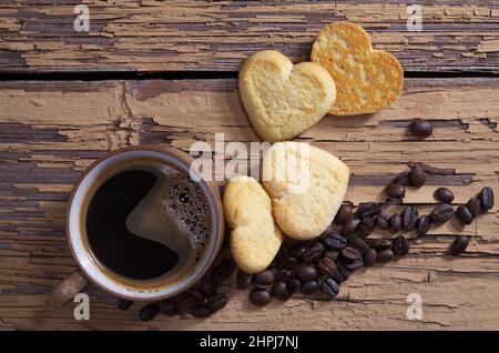 Tasse de café et biscuits sablés en forme de coeur sur fond de bois vintage, vue du dessus Banque D'Images