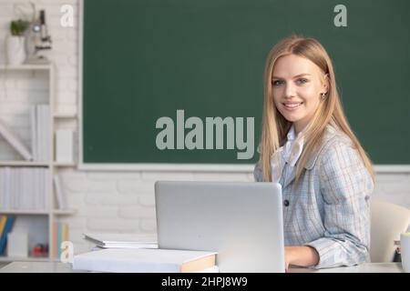 Adorable jeune fille, élève de l'école écrire des notes, regarder la vidéo en ligne webinaire, apprendre sur ordinateur portable, s'asseoir dans la salle de classe, cours d'apprentissage à distance en ligne. Banque D'Images