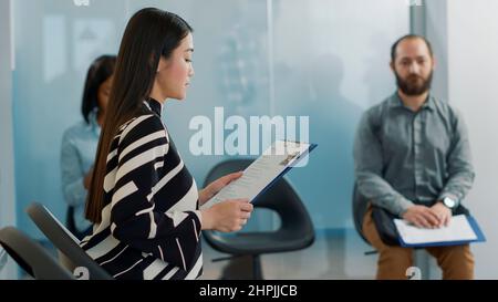 Une travailleuse enceinte invite une candidate à participer à une entrevue d'emploi avec l'équipe des RH dans le bureau de l'entreprise. Le candidat et l'employé se joignent à la réunion d'emploi, avec des fichiers d'information de cv. Banque D'Images