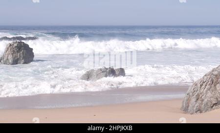 Grandes vagues immenses de l'océan pacifique se brisant sur une plage de sable, puissance de la nature, marée de mer eau mousseuse barbotant à côté de la côte. Garrapata Park, Big sur, côte californienne, États-Unis. Paysage de mer et rochers, temps brumeux brumeux. Banque D'Images