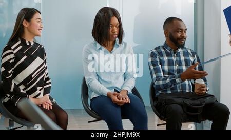 Employé de bureau donnant cv à divers groupes de candidats, assistant à un entretien d'emploi et attendant dans le hall d'entrée. Candidats en file d'attente avec dossiers de recrutement, en préparation de la réunion d'embauche. Banque D'Images