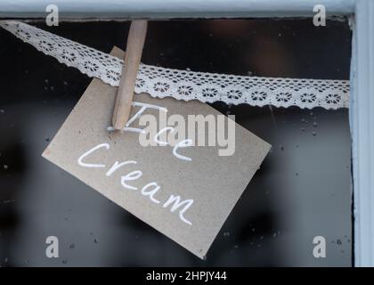 Affiche de crème glacée accrossée à la dentelle dans la fenêtre du magasin annonçant les desserts de glace aux clients du café à emporter Banque D'Images