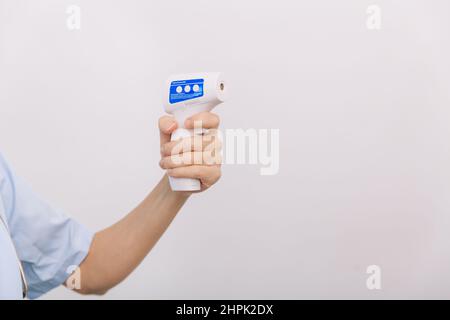 Pistolet de mesure de température dans les mains du médecin.Gros plan d'un médecin portant un masque chirurgical de protection prêt à l'emploi thermomètre infrarouge isométrique Banque D'Images