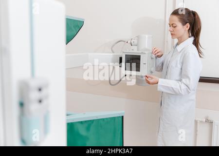 Salle de radiologie de l'hôpital. Appareil à rayons X pour la radiographie. Médecin radiologue en casaque en ajustant la machine à rayons X pour la radiographie. Équipement médical Banque D'Images