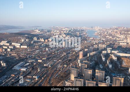 Vladivostok, Russie - 5 février 2022 : Vue d'en haut des maisons et des rues de la ville. À l'horizon, vous pouvez voir la mer et les ponts. Banque D'Images