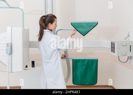 Salle de radiologie de l'hôpital. Appareil à rayons X pour la radiographie. Médecin radiologue en casaque en ajustant la machine à rayons X pour la radiographie. Équipement médical Banque D'Images